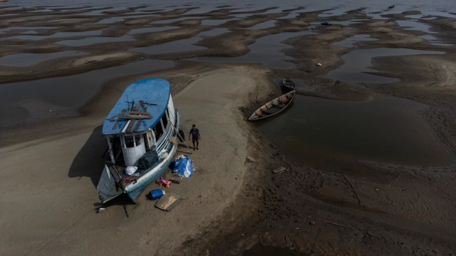 Com o aquecimento global, Amazônia enfrenta seca severa com embarcação atolada em rio seco