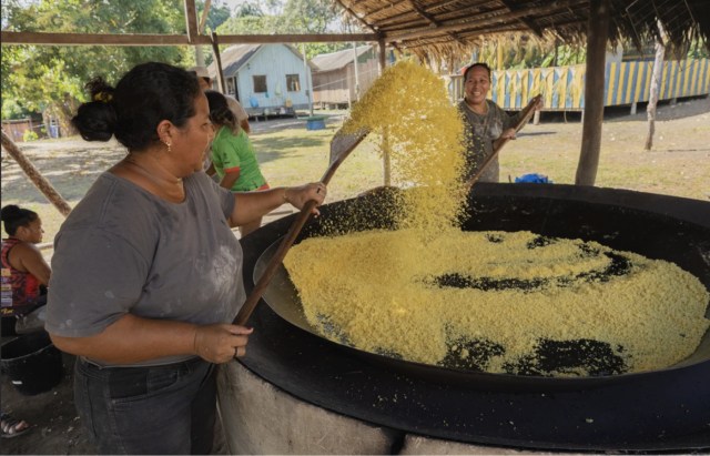 Conceição Parintintin e a irmã Maria de Lourdes mexendo a farinha de mandioca para não queimar