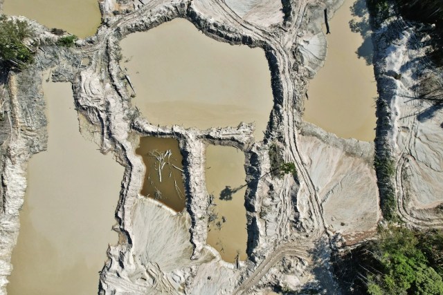 Crateras alagadas deixadas pelo garimpo na terra Munduruku, com áreas desmatadas e solo exposto.